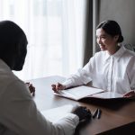 Grupo diverso conversa sobre documentos com um profissional durante atendimento de assistência social em uma residência.