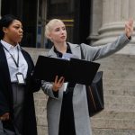 Mulheres com crachás conversam em um escritório público sobre um projeto para a cidade.
