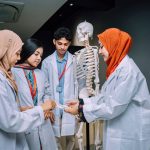Estudantes de medicina analisam um esqueleto em uma sala de aula.