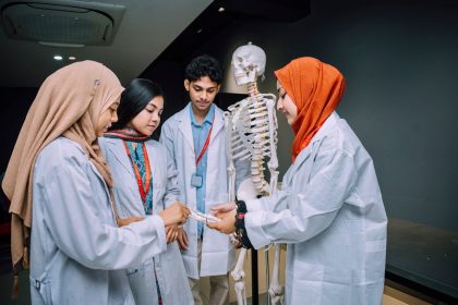 Estudantes de medicina analisam um esqueleto em uma sala de aula.