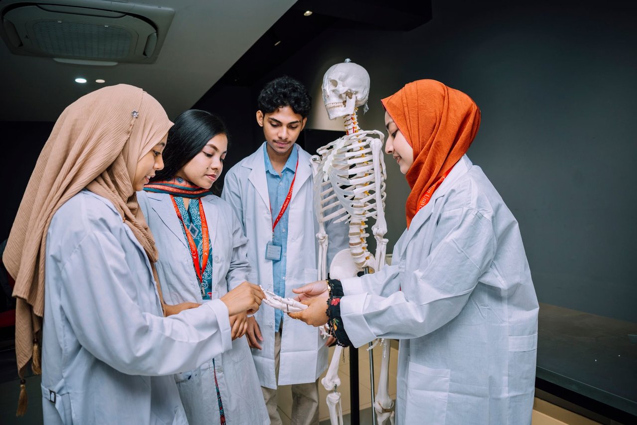 Estudantes de medicina analisam um esqueleto em uma sala de aula.
